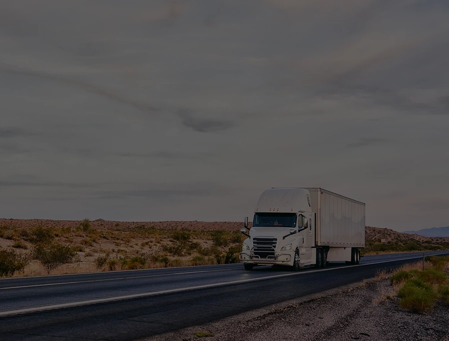 Smiling truck driver sitting in the cab, looking at the camera in warm evening light.